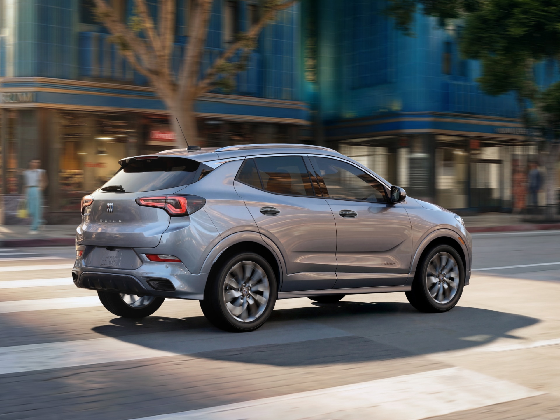 A Gray Buick Encore GX Driving Away on a City Street Crossing a Crosswalk