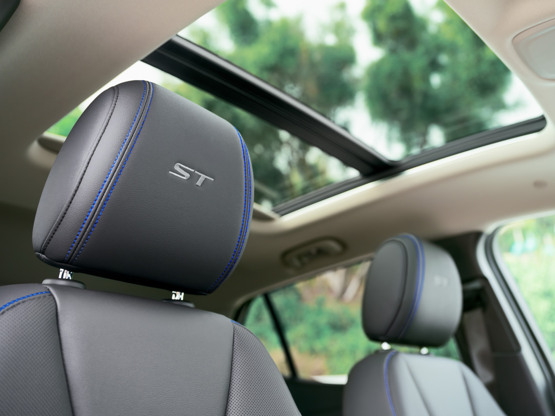 Gray Leather Headrests with "ST" Embroidered in Silver and Blue Stitching, Below an Open Sunroof