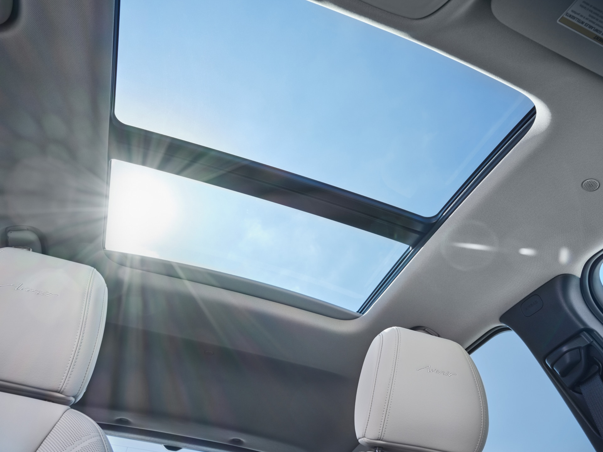 Open Sunroof in a Buick Vehicle, with Bright Blue Sky and Sun Rays Shining into the Interior