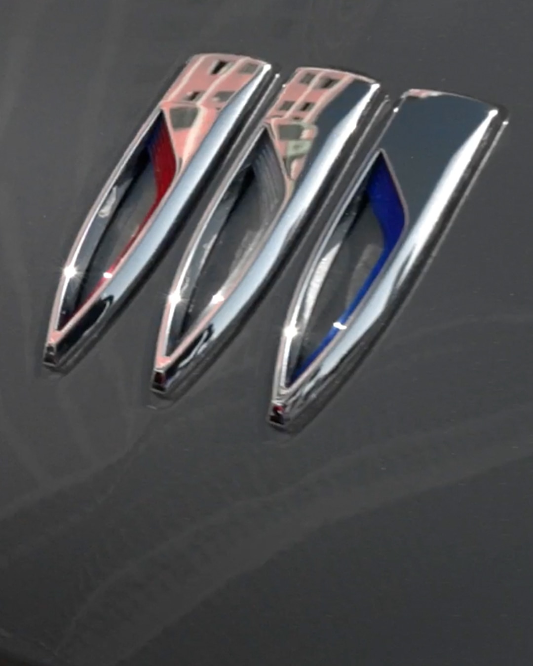 Close-up of the Buick Logo on the Hood of a Dark Vehicle with Faint Swirls
