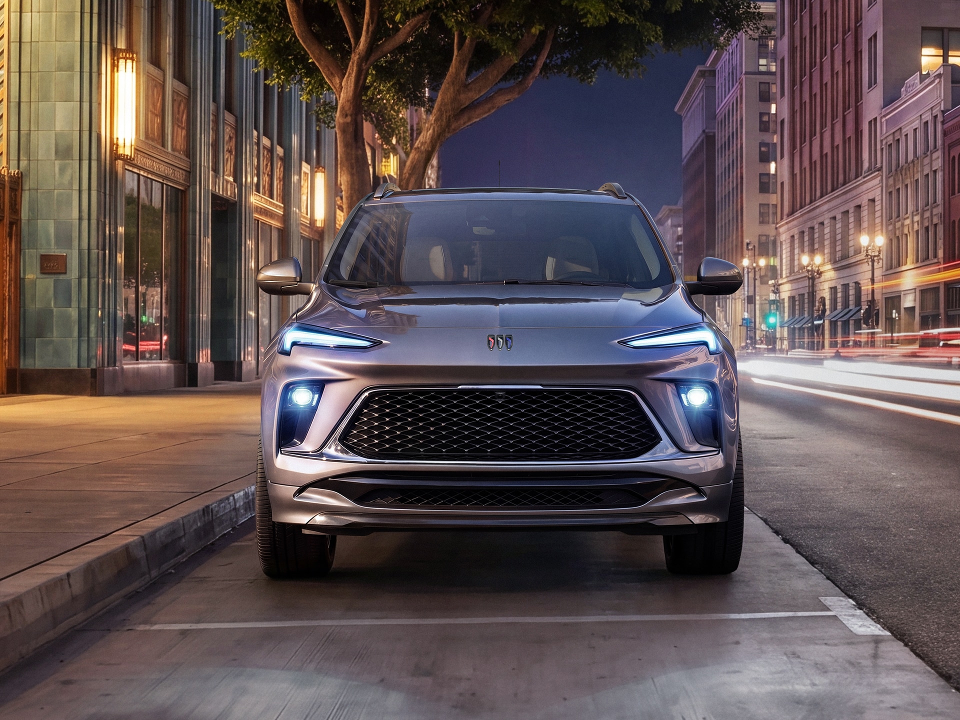 A Gray Buick Encore GX Parked on a City Street at Night with Light Trails