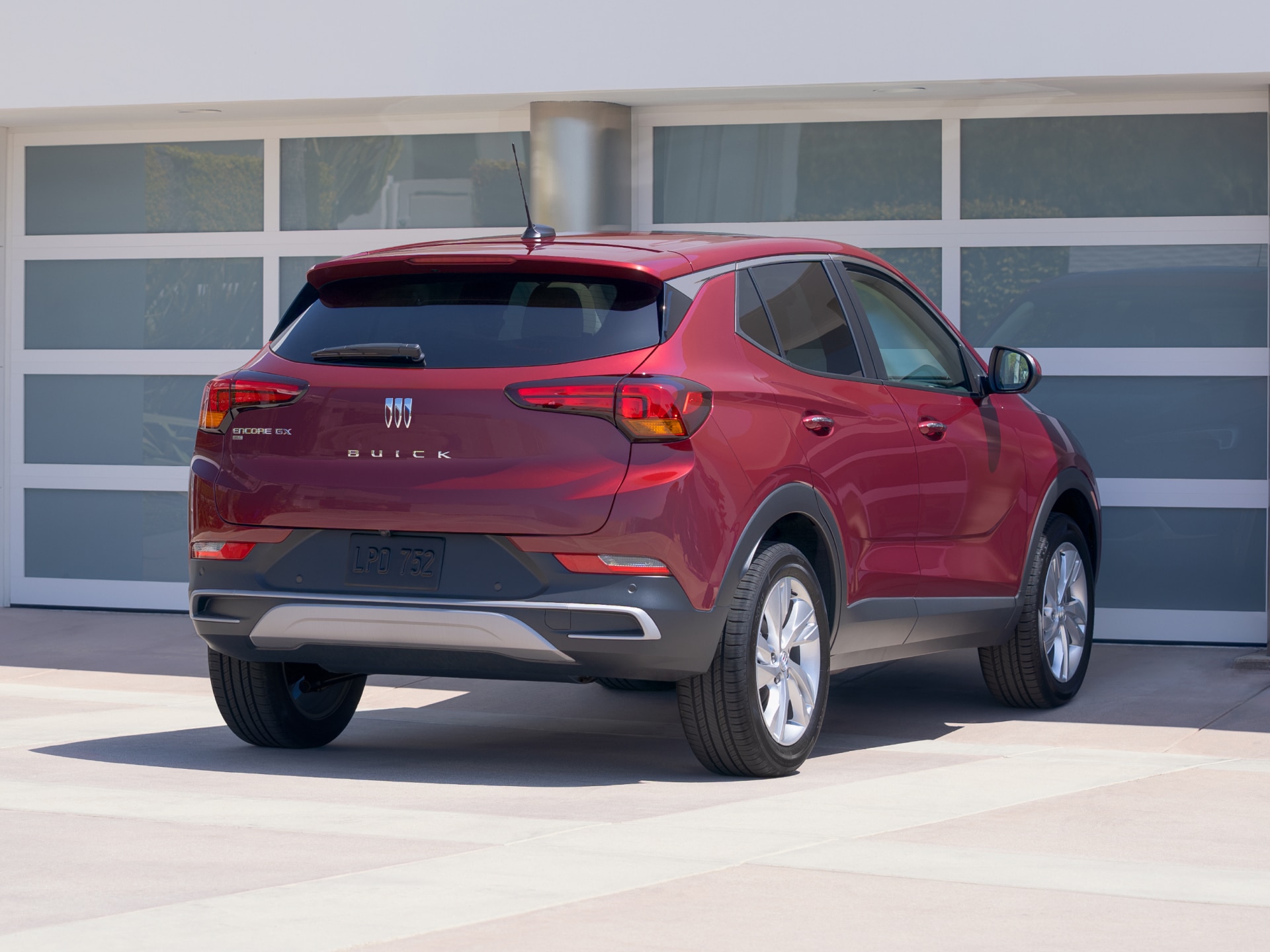 A Red Buick Encore GX Parked in Front of a Modern Garage with Horizontal Glass Panels