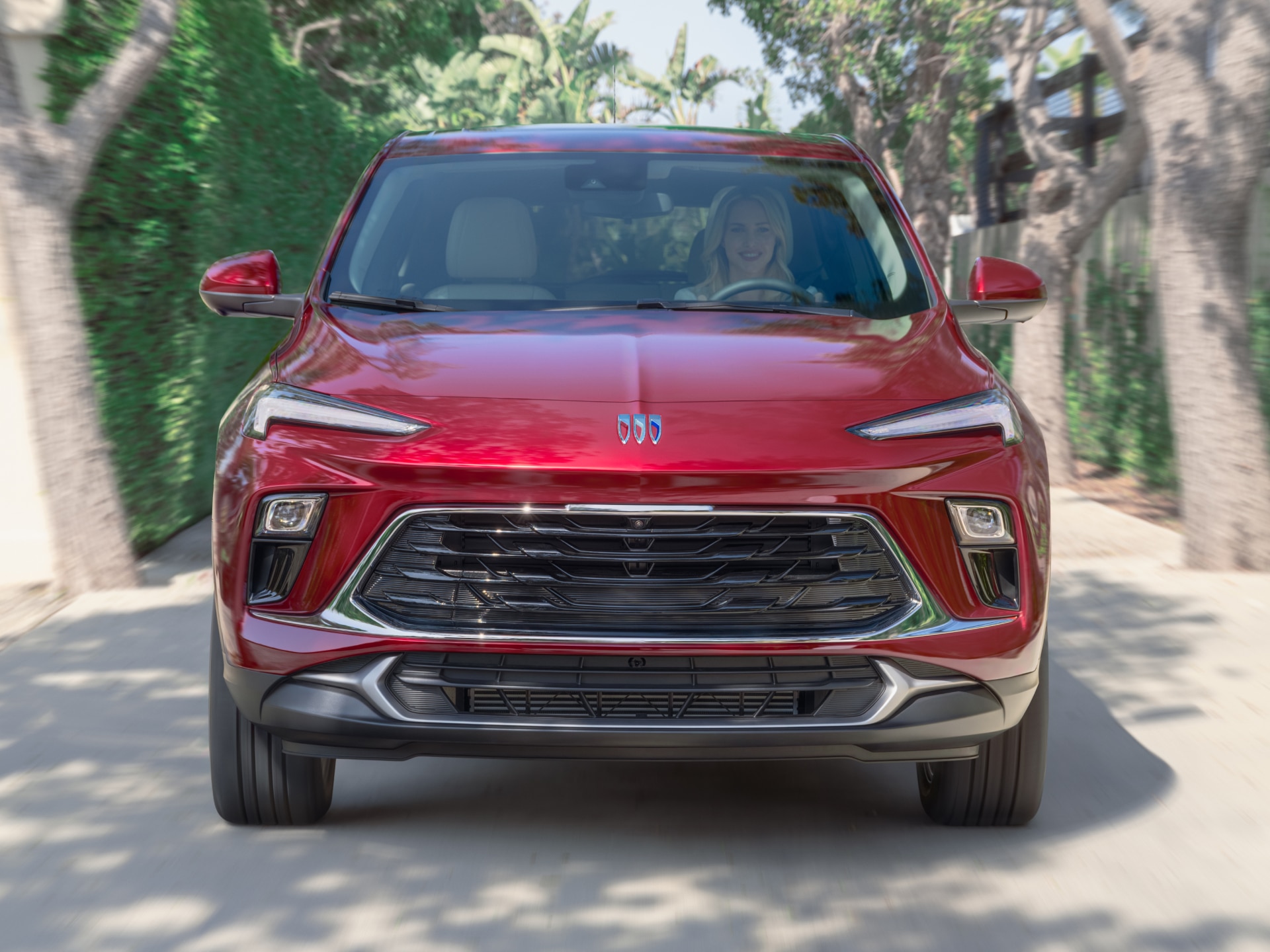 A Red Buick Encore GX Driving on a Paved Road with a Woman Driver