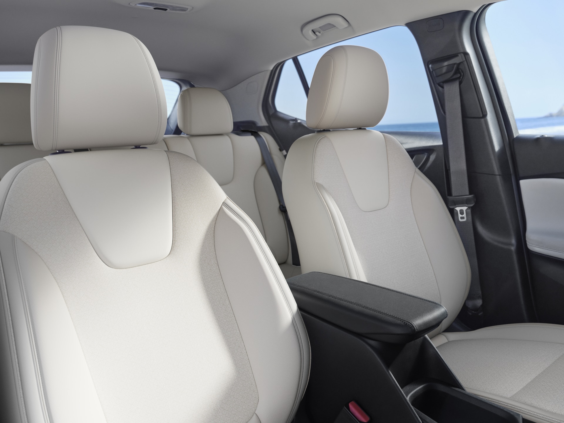 The Interior of a Buick Vehicle with Light-Colored Seats and an Armrest with the Ocean in the Background