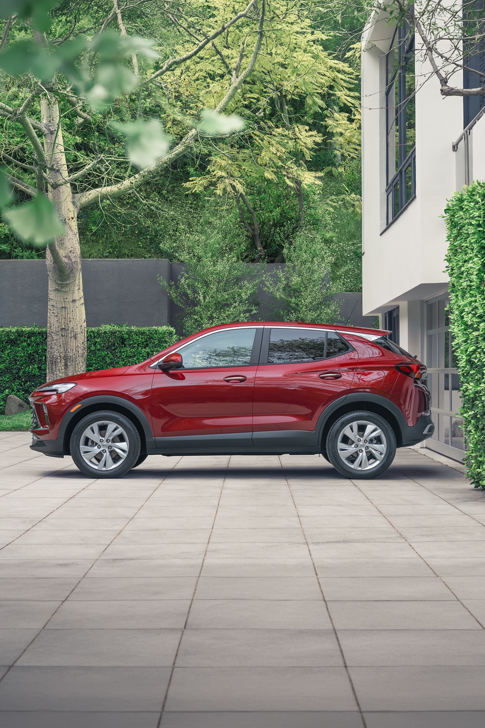 The Side Profile of a Red Buick Encore GX Parked on a Paved Driveway