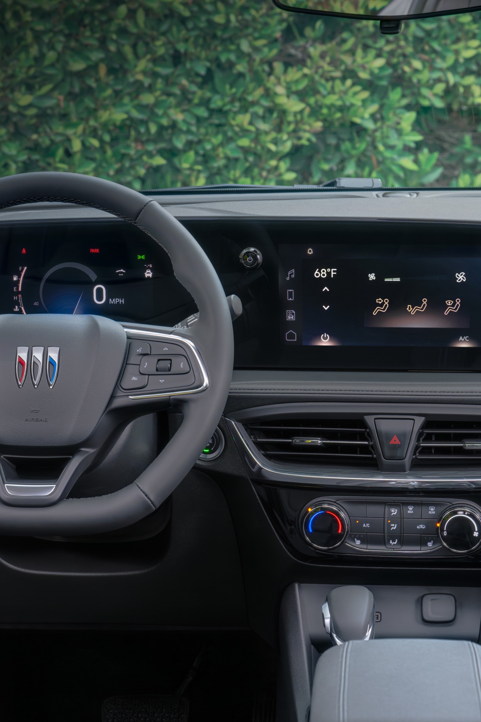 Interior Dashboard View of a Buick Car, Showing the Steering Wheel with the Buick Logo, Digital Instrument Cluster, and a Large Infotainment Screen Displaying Climate Controls