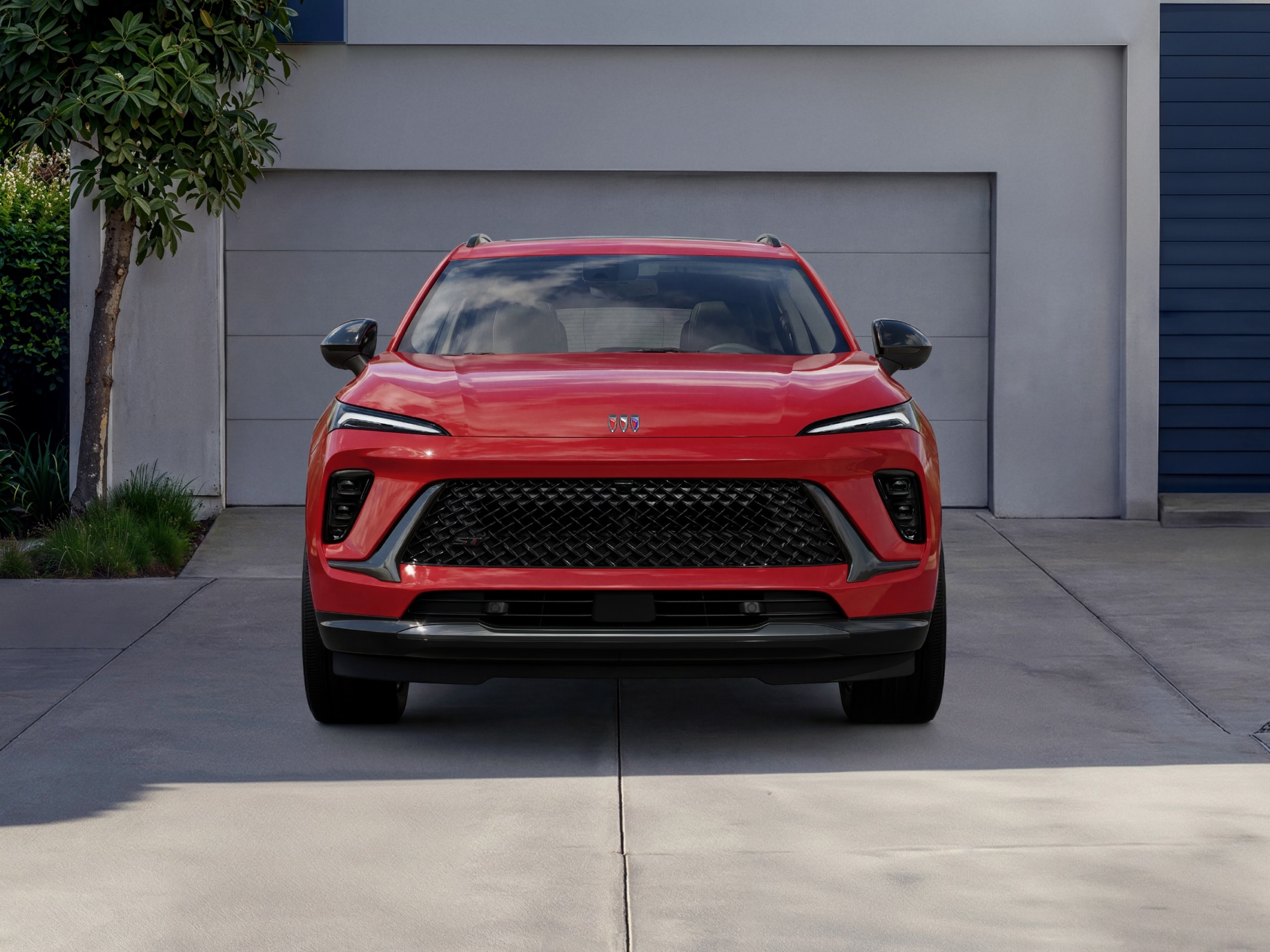 A Red 2027 Buick Envision SUV Parked in a Driveway with a Modern Garage in the Background
