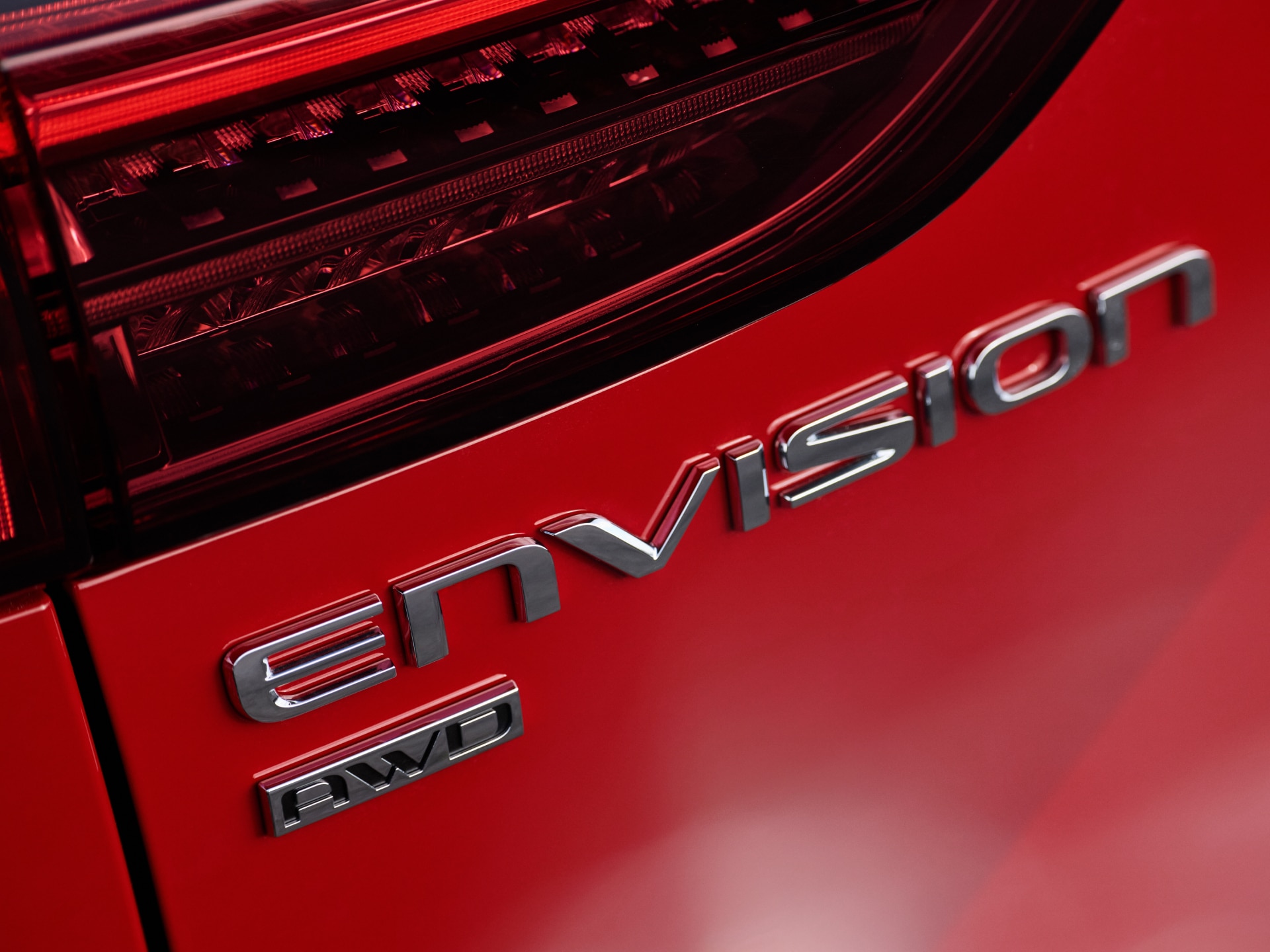 A Close-Up View of the Buick Envision and AWD Badges on a Red 2027 Model's Rear