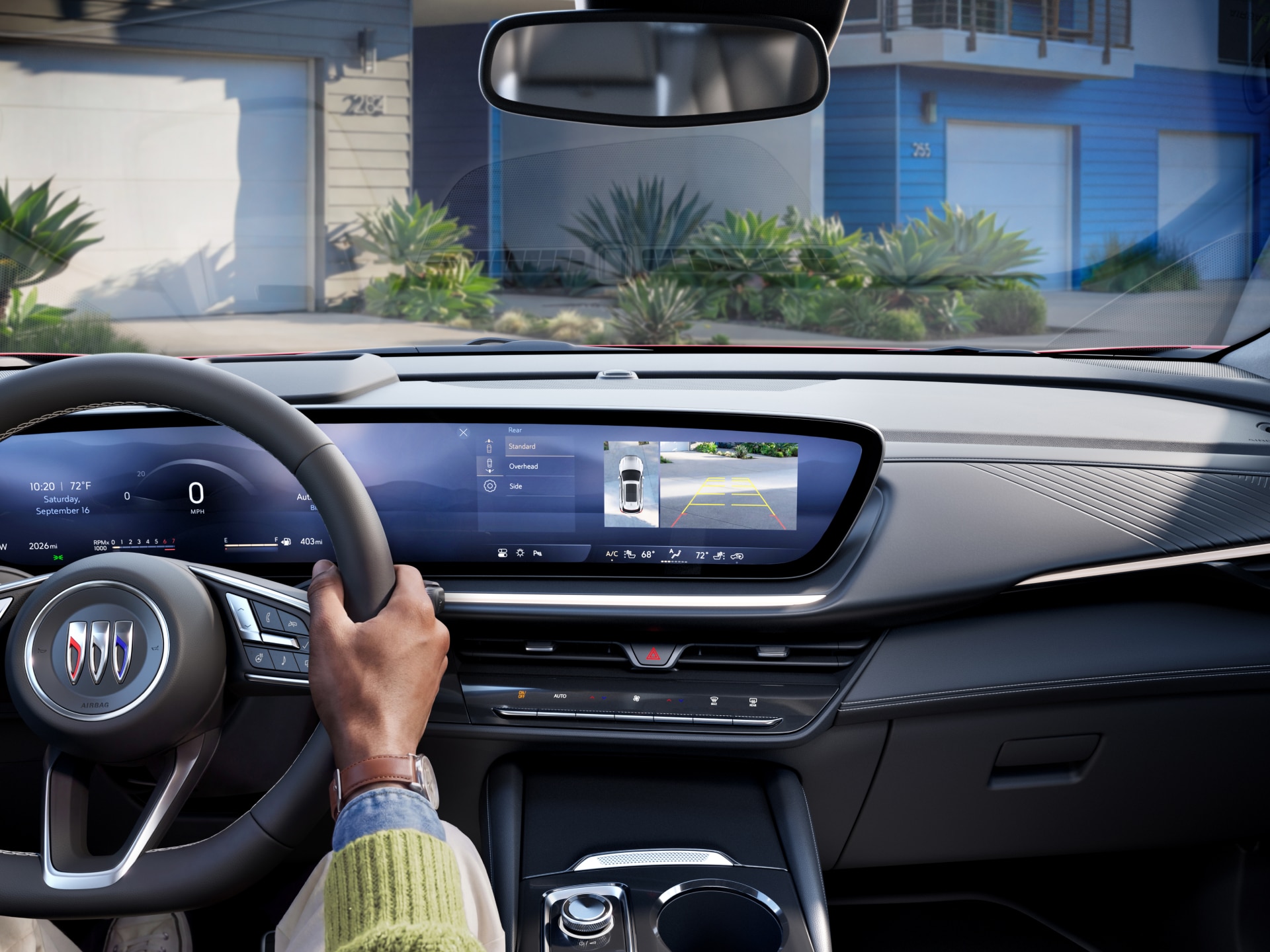 Driver's Perspective Inside the 2027 Buick Envision with Hands on the Steering Wheel and the Infotainment Screen Displaying a Backup Camera