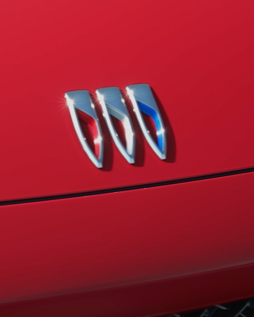 Close-Up of the Chrome Buick Logo Emblem on the Hood of a Red 2027 Buick Envision