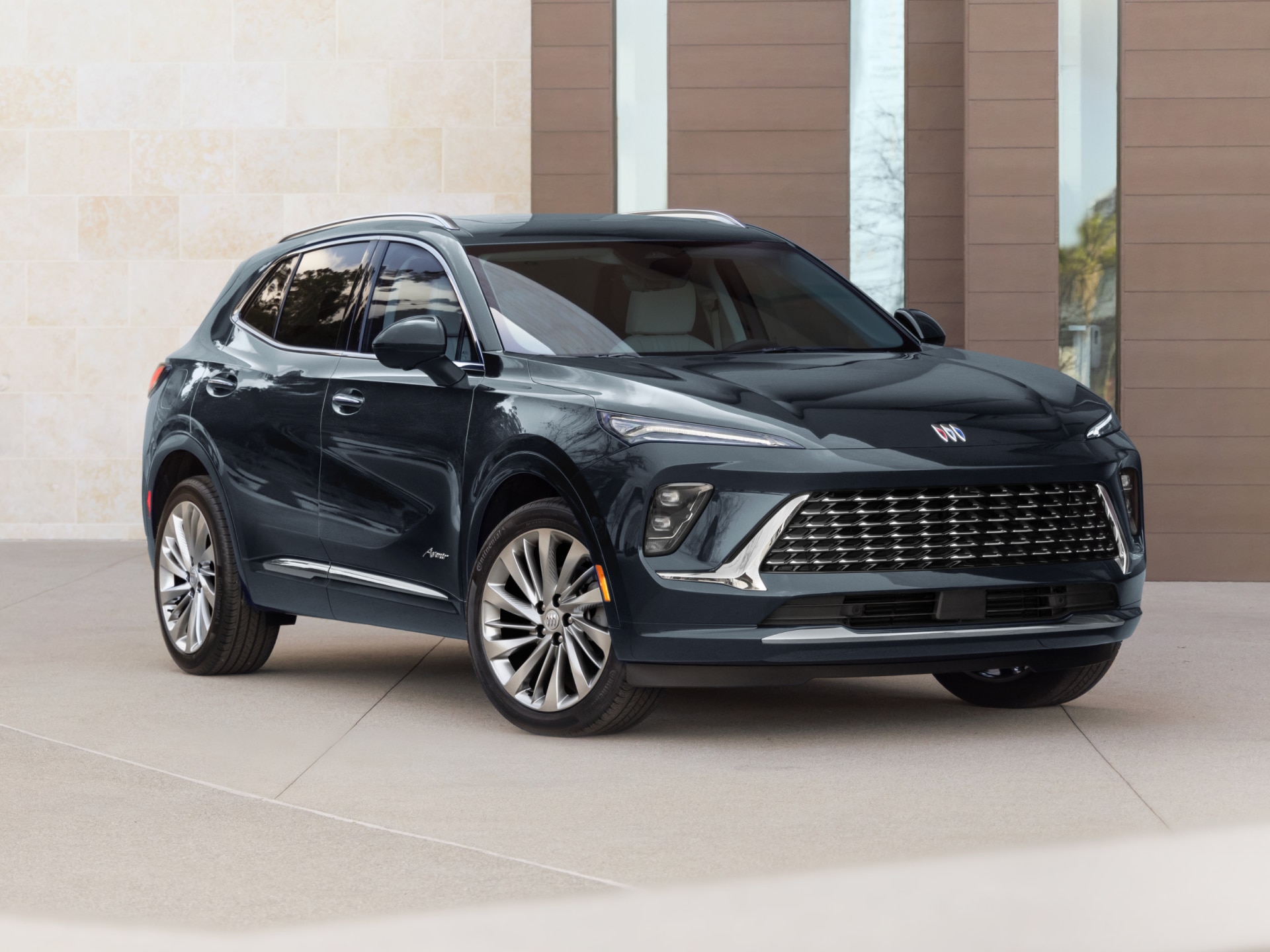 A Dark Blue Buick SUV Angled Towards the Left with a Modern Building in the Background