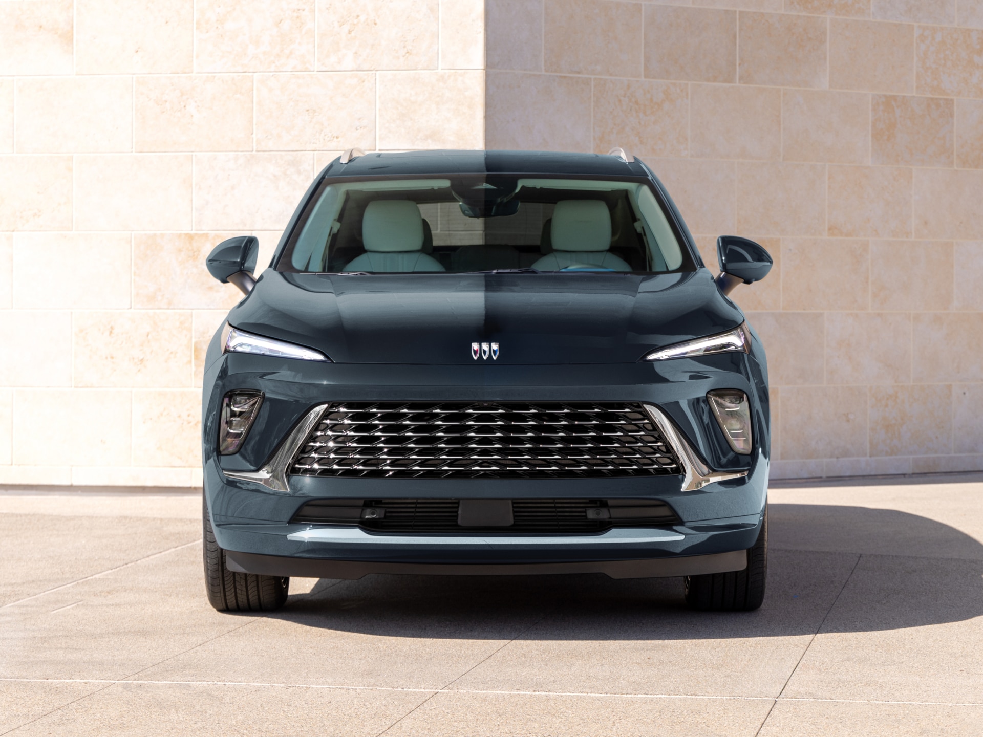 A Dark Blue Buick SUV Front View Parked in Front of a Textured Wall
