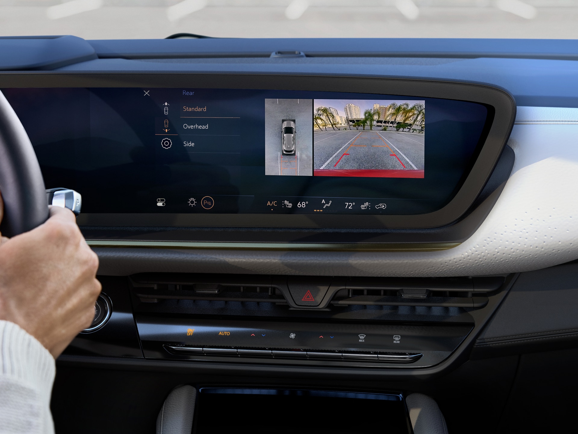 Driver's View of a Buick Interior with a Hand on the Steering Wheel and Backup Camera Display