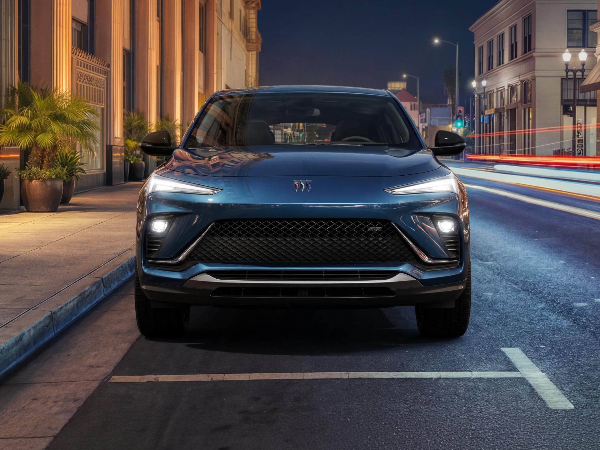 The Front View of a Dark Blue Buick Envista Parked on a City Street At Night with Building Lights and Traffic Streaks