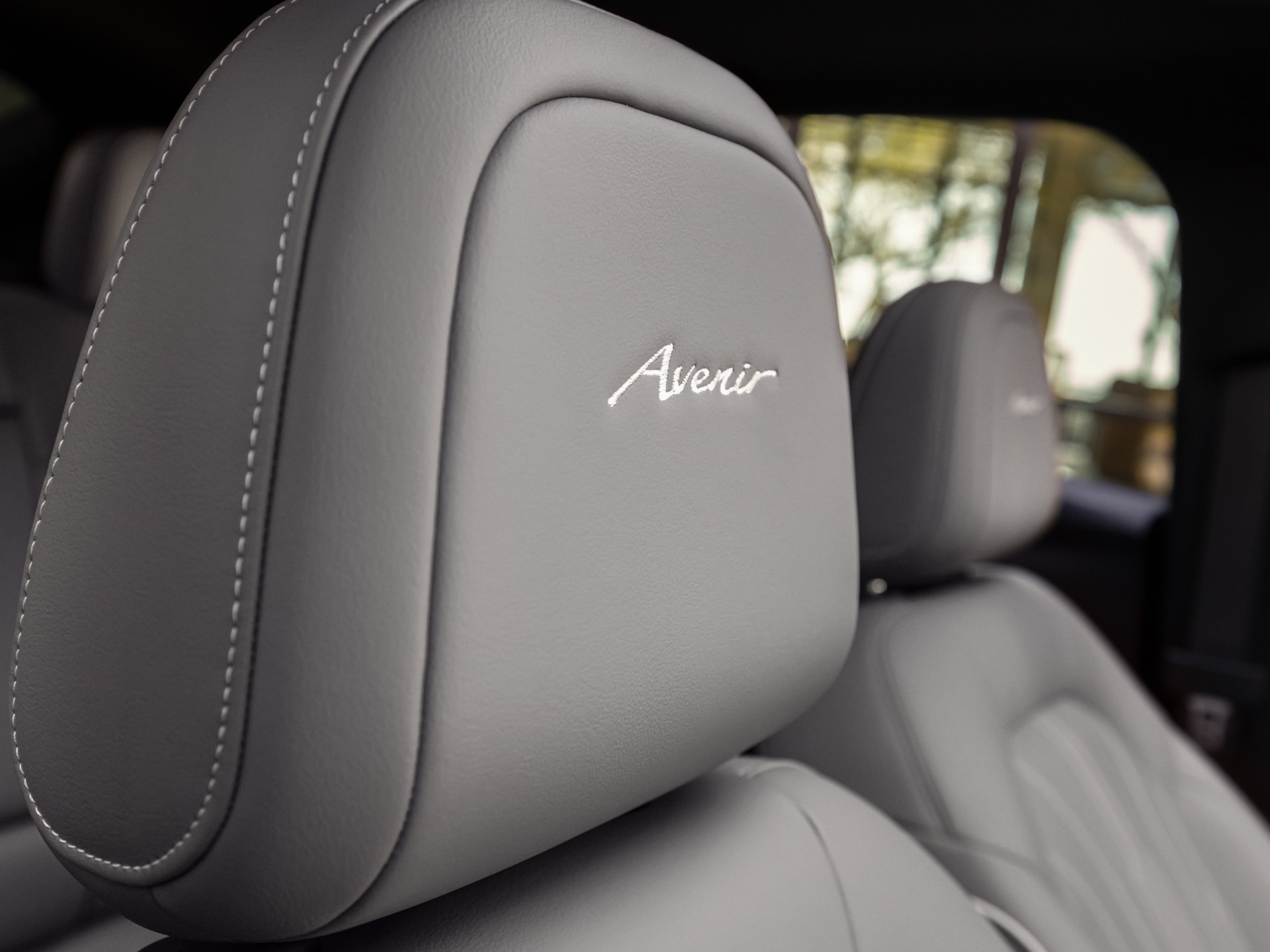A Close-up of a Gray Leather Headrest with the Buick Avenir Logo Embroidered in White Stitching