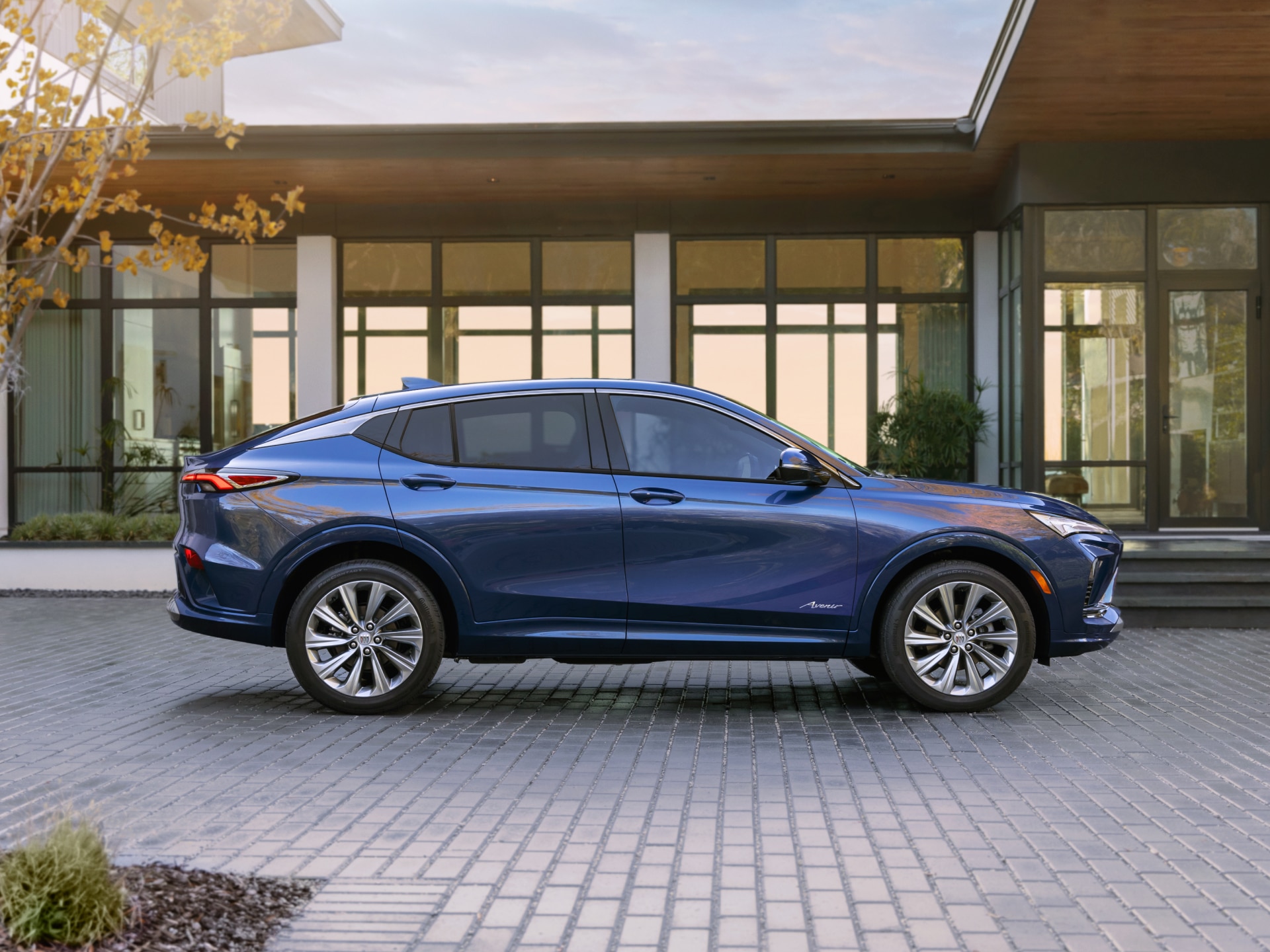 A Side Profile of a Blue Buick Envista Parked in Front of a Modern House