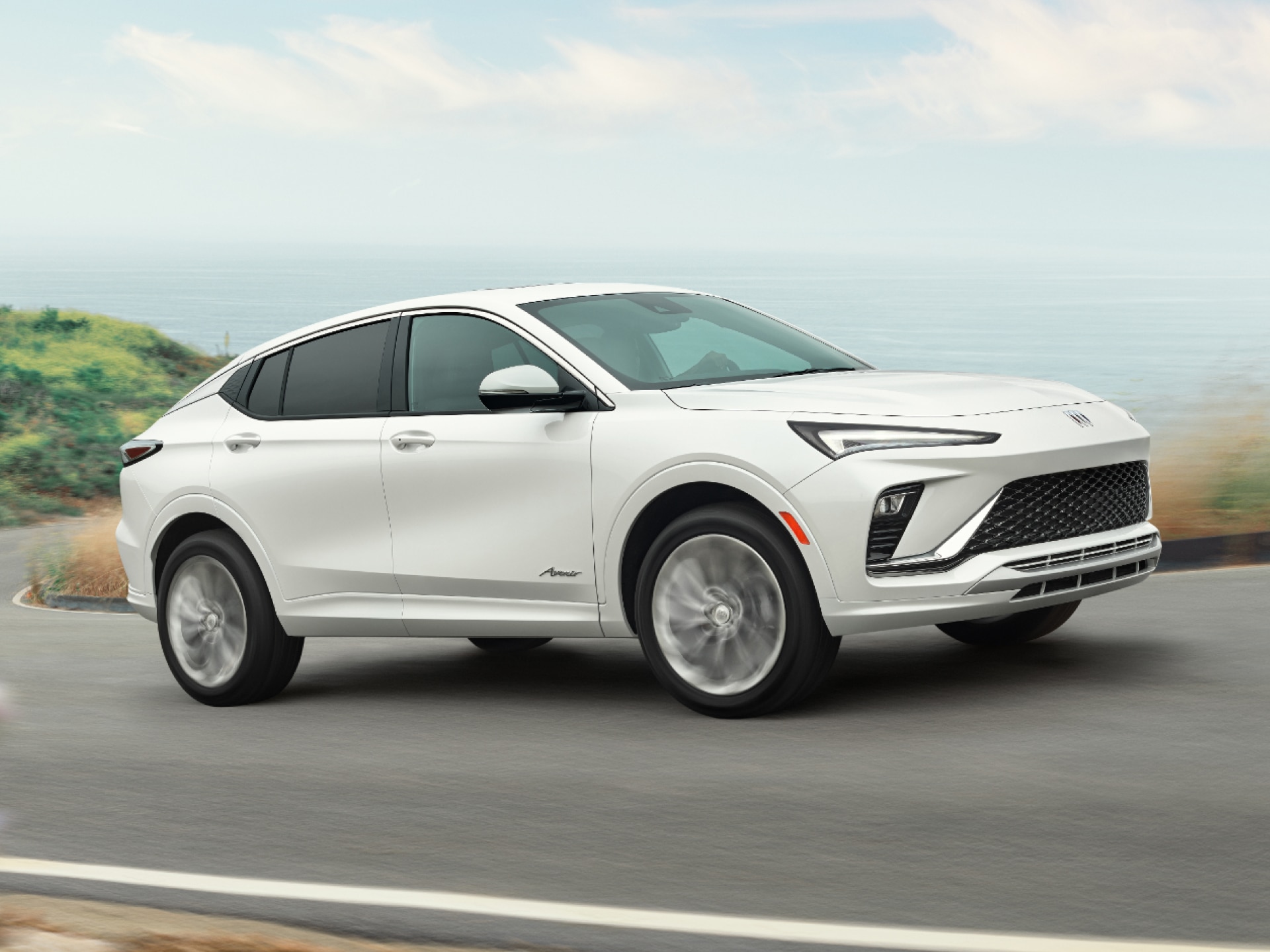 A White Buick Envista Driving on a Winding Road with a View of the Ocean
