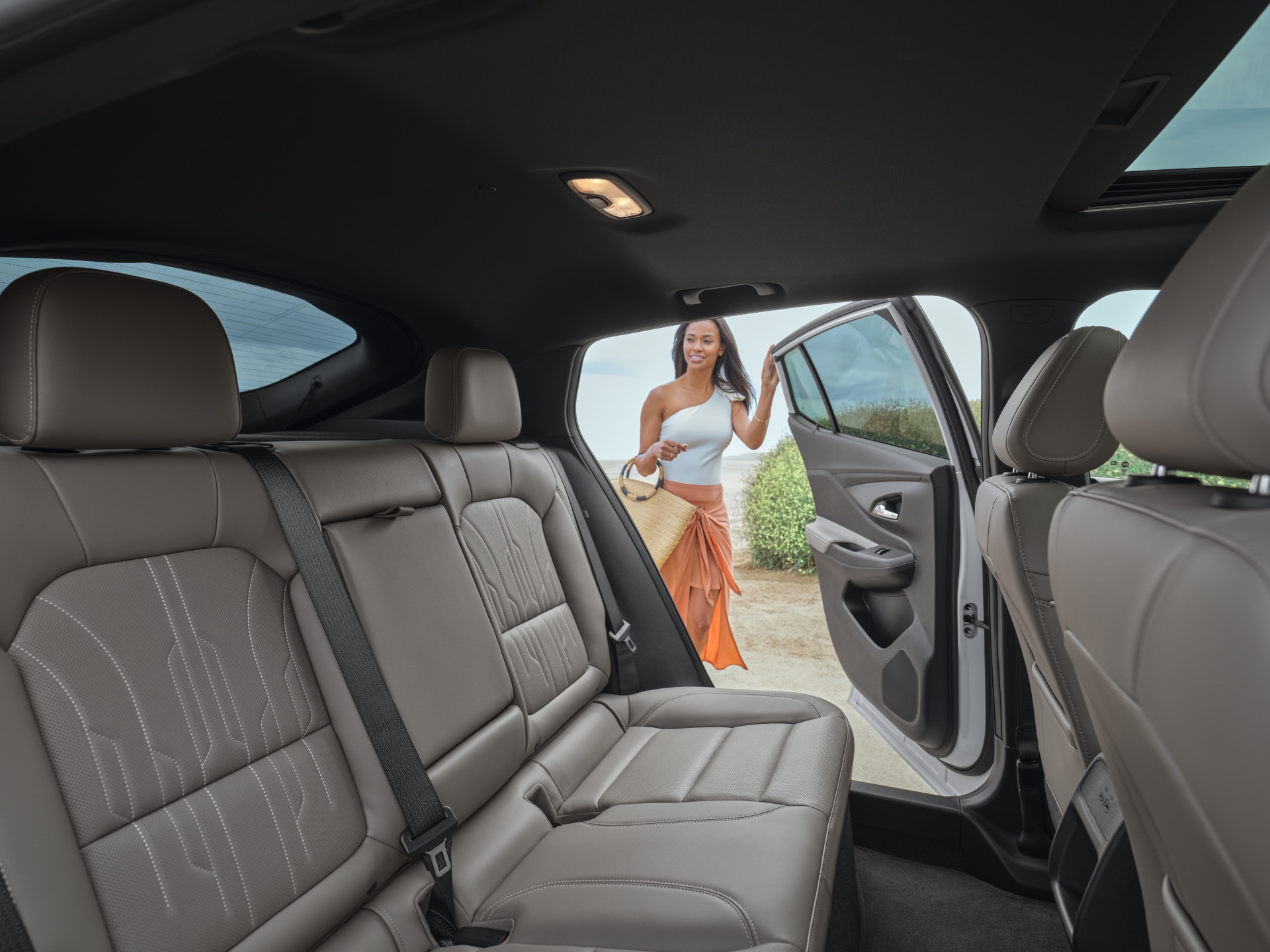 A Woman Stepping into the Rear Passenger Seat of a Buick SUV with Brown Leather Seats