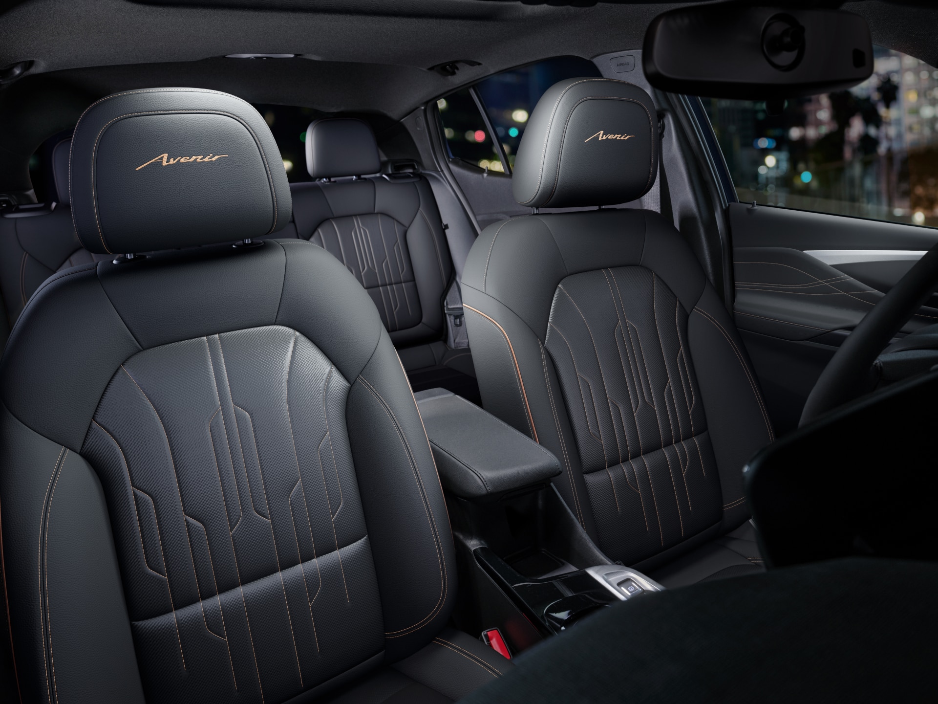 The Interior View of the Front and Rear Seats of a Buick Avenir with Dark Leather and Copper Stitching at Night