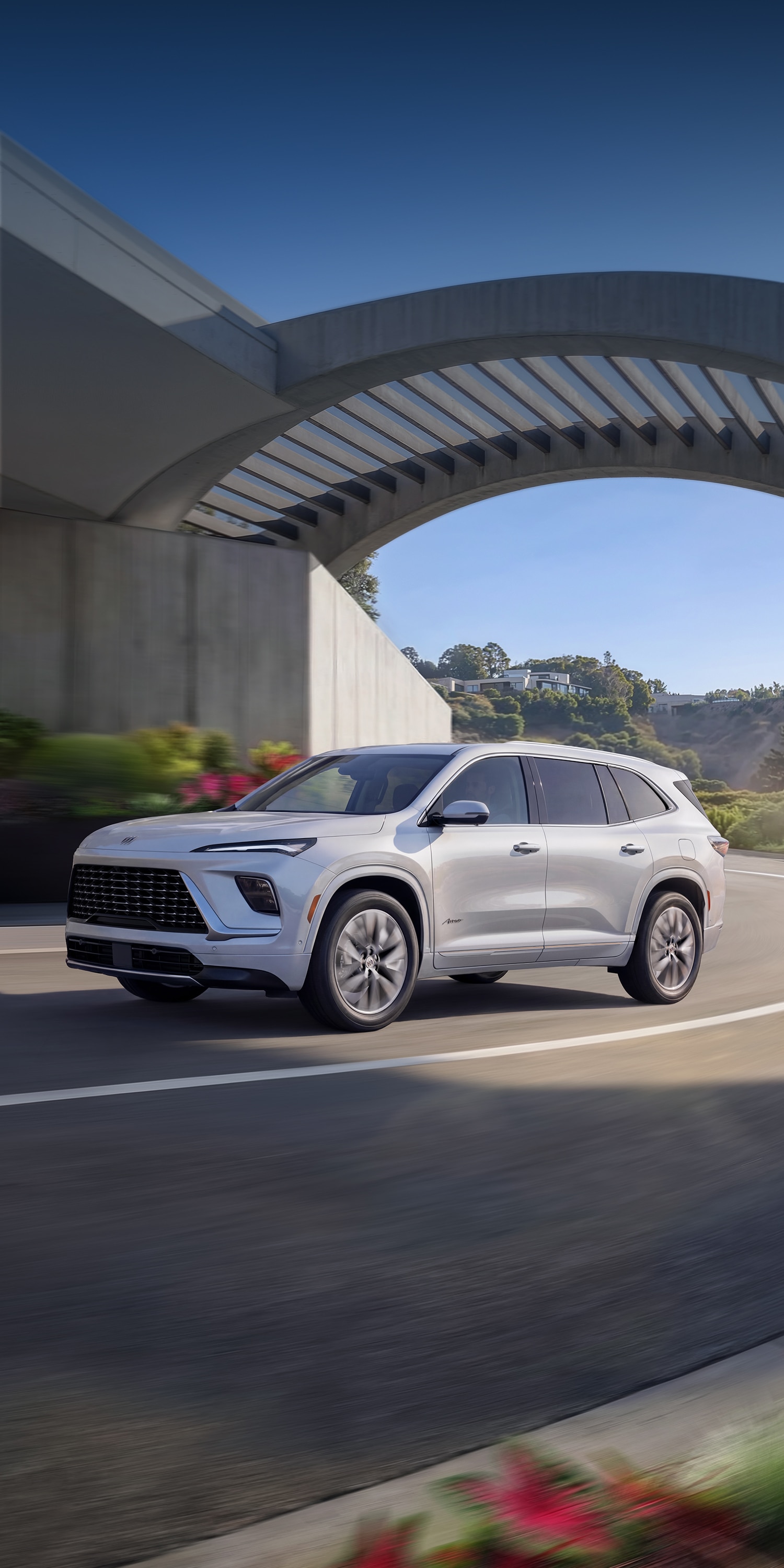A White Buick Enclave SUV Driving Away on a Scenic Road