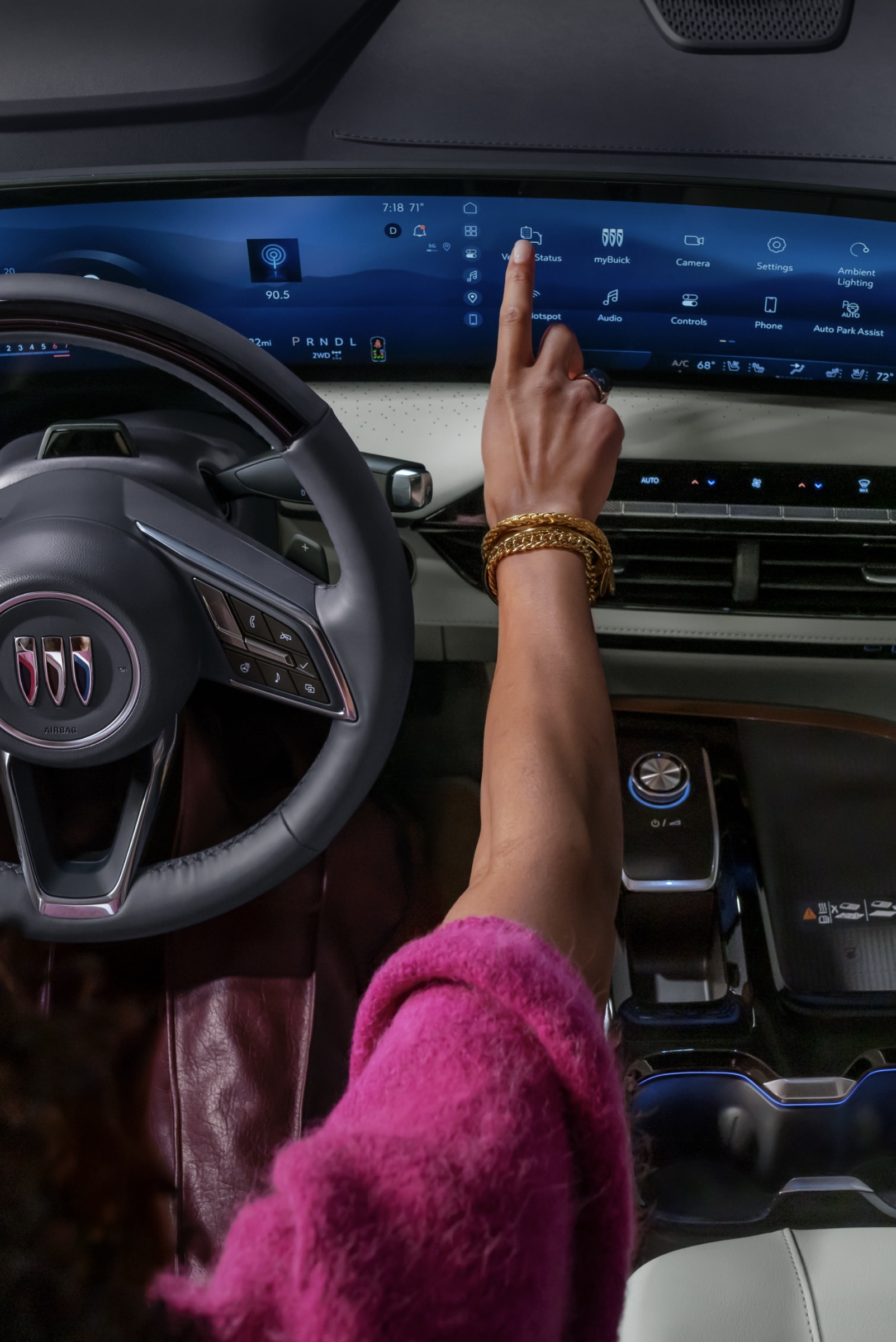 A Driver's Hand Interacts with the Expansive Curved Digital Display in a Modern Buick Interior, Featuring the Buick Logo on the Steering Wheel