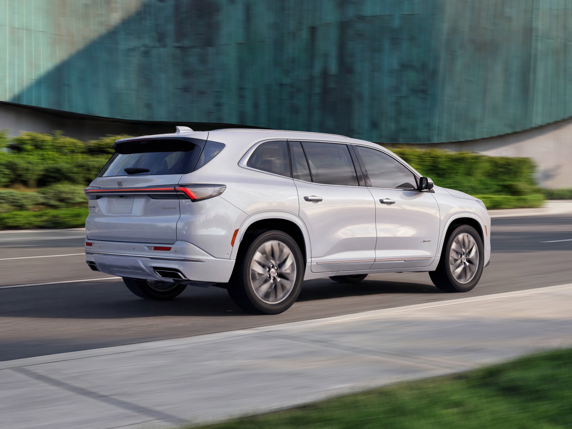 The Rear Angle of a White Buick Enclave Avenir SUV Driving on a Road