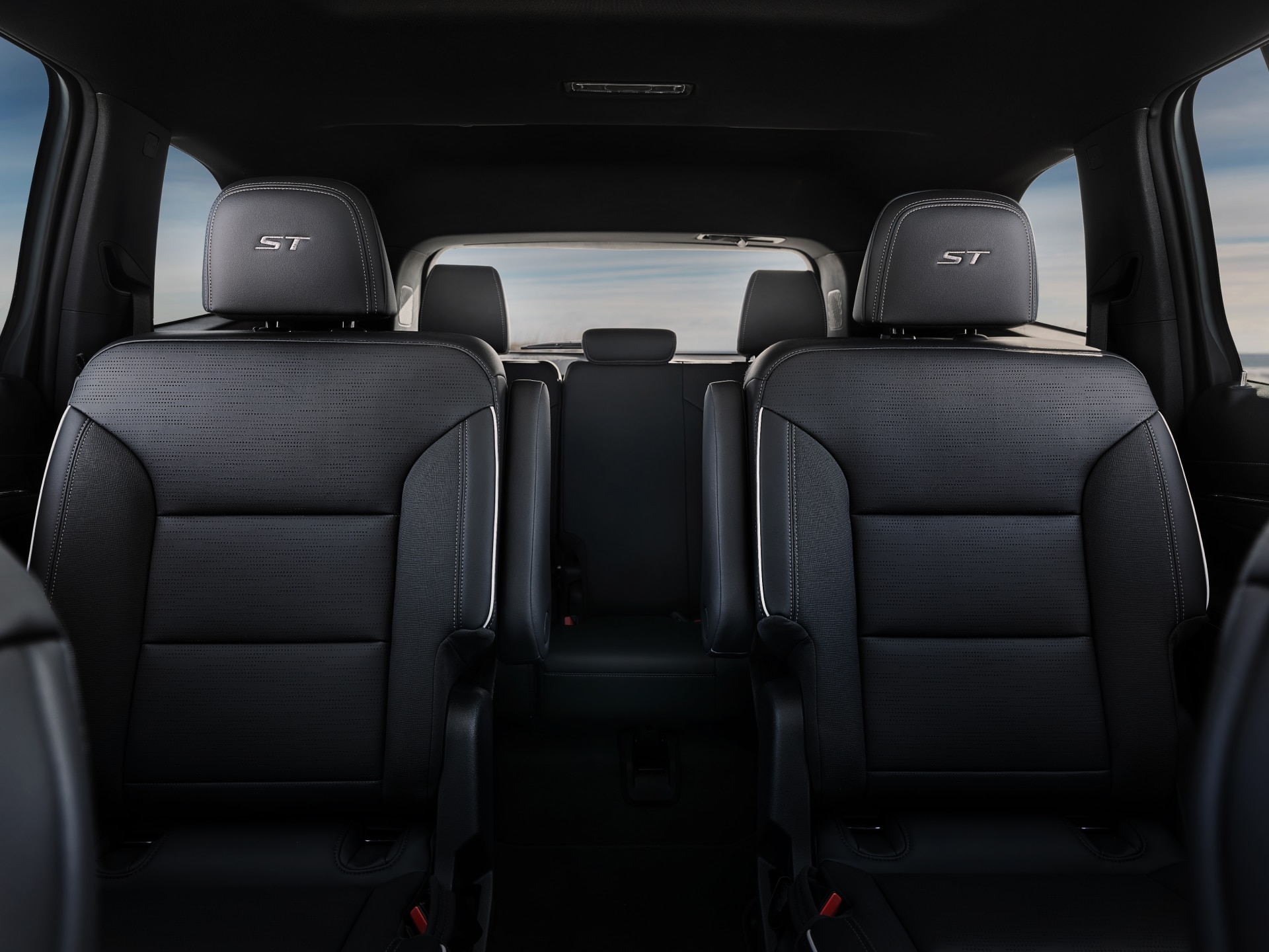 The Interior of a Buick Vehicle with Dark-Colored Second and Third-Row Seats and ST Emblems on the Headrests