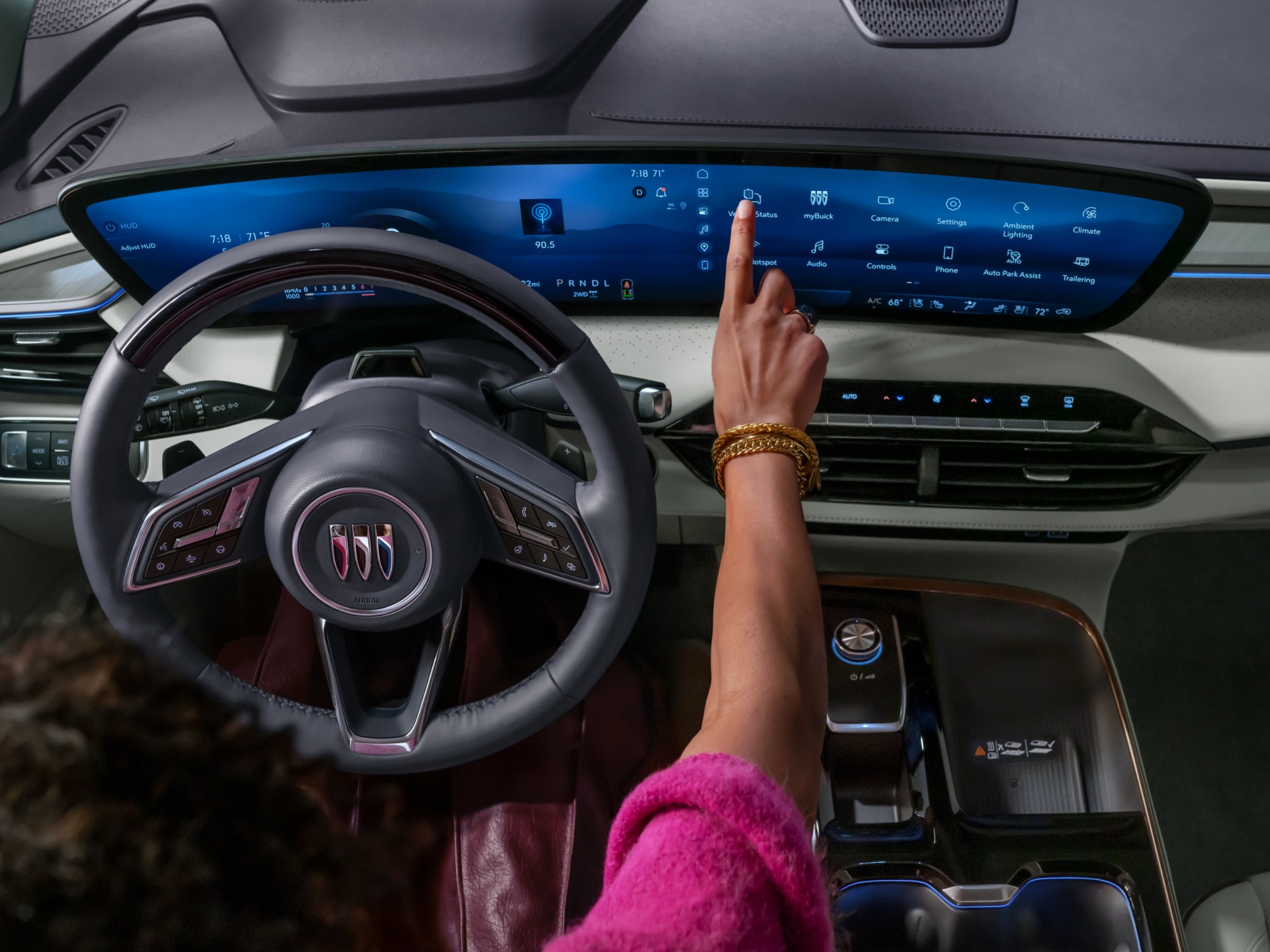 A Driver's Hand Interacts with the Expansive Curved Digital Display in a Modern Buick Interior, Featuring the Buick Logo on the Steering Wheel