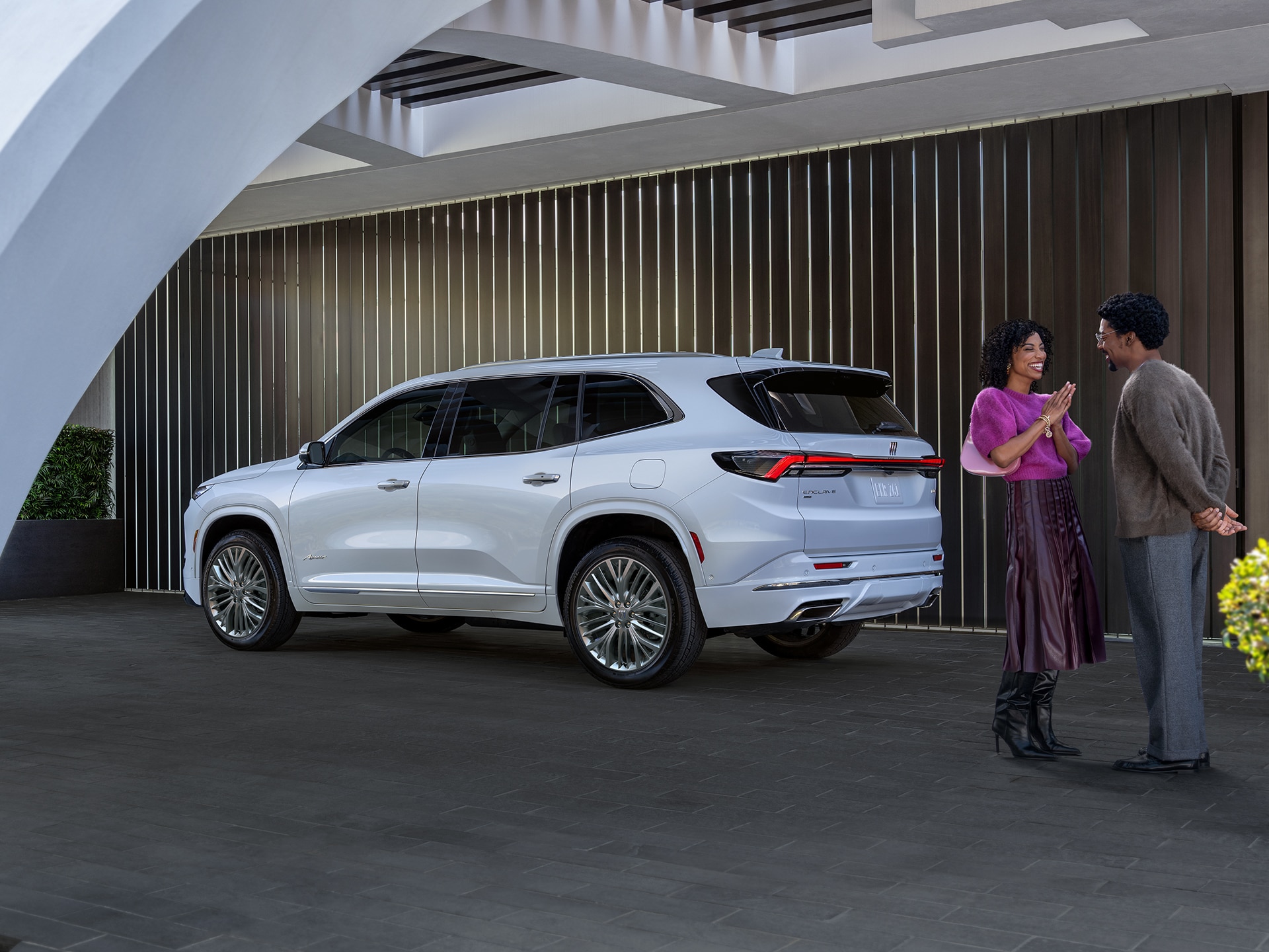 A Man and a Woman Standing Near a White Buick Enclave Parked in a Driveway