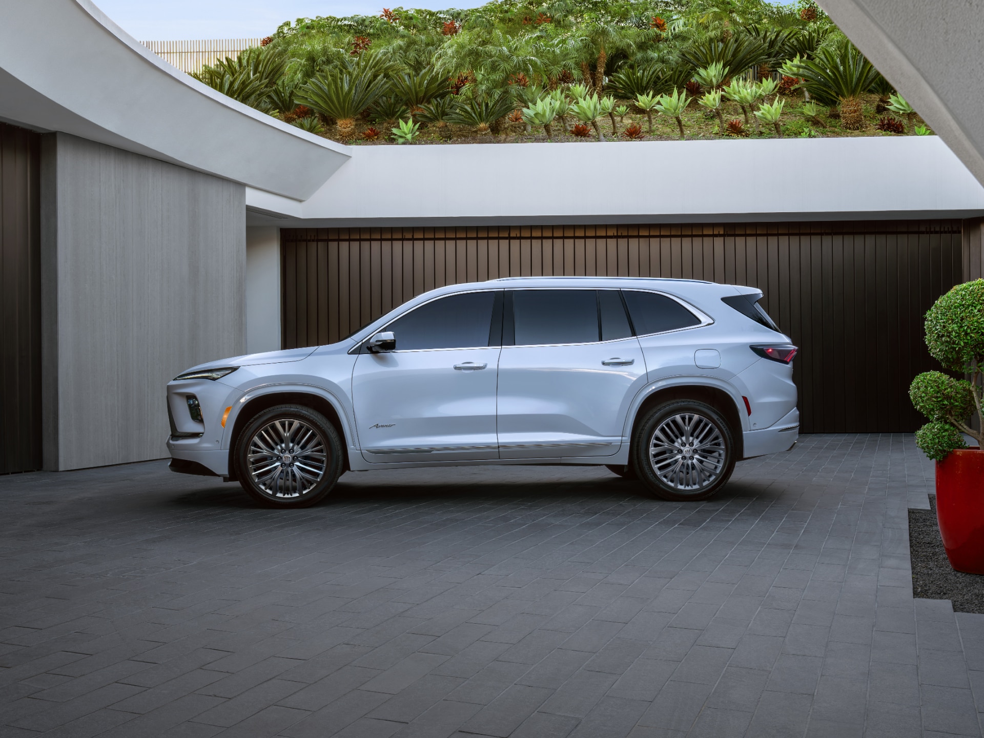 A White Buick Enclave SUV Parked on a Driveway in Front of a Modern Garage