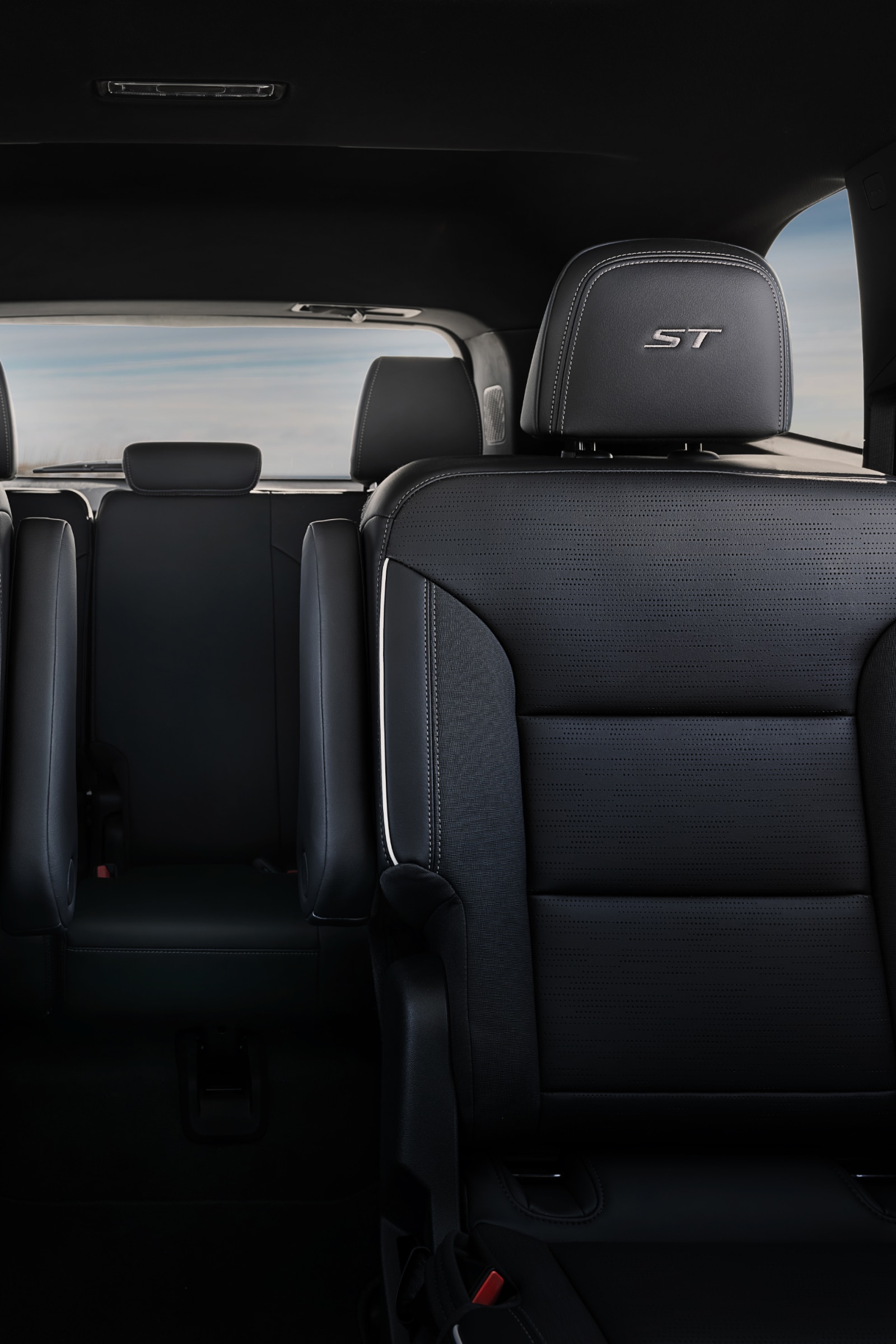 The Interior View of the Rear Passenger Seats of a Buick with Three Rows of Dark Gray Seats