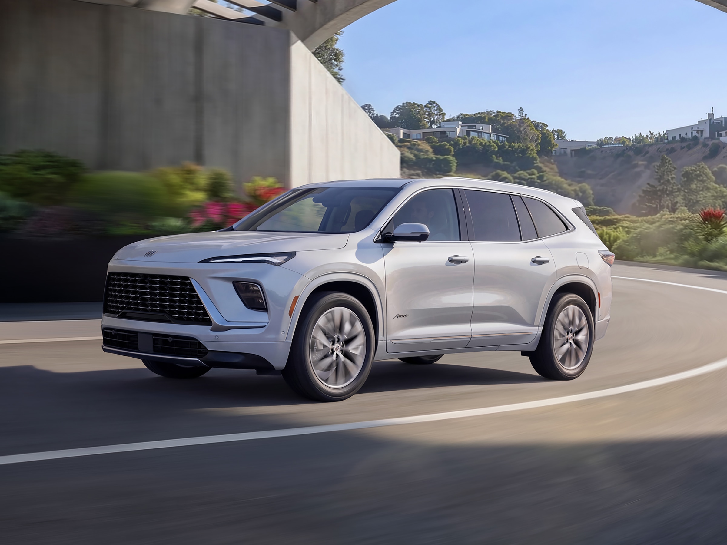 Profile View of the 2026 Buick Enclave in Iridescent White Tricoat Driving on a Curvy Road