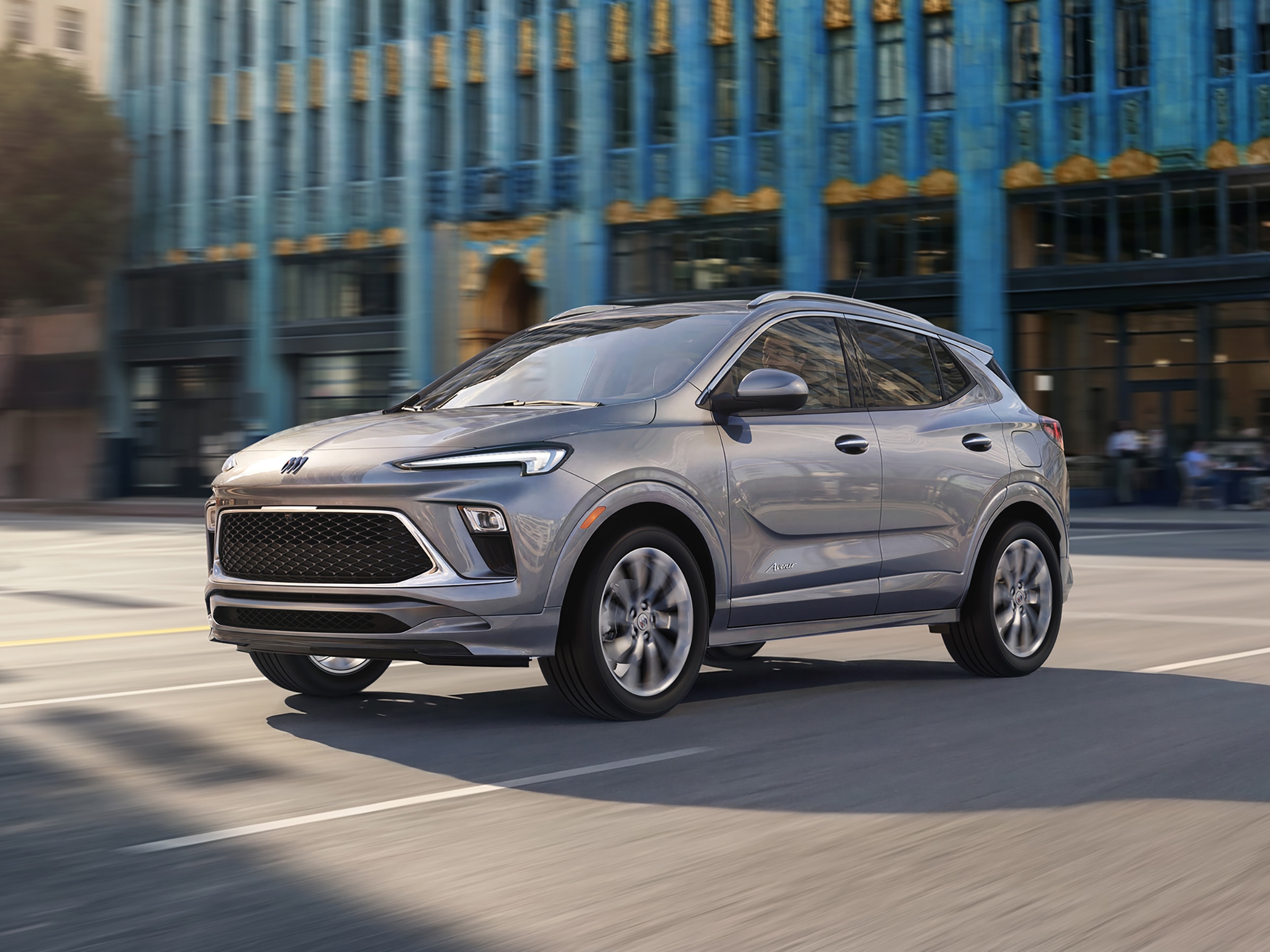 Profile View of the 2026 Buick Encore GX in Moonstone Gray Metallic Driving Through a City