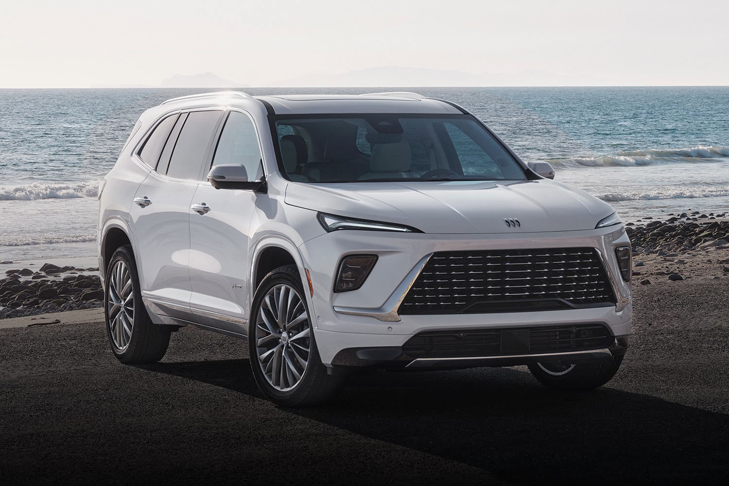 A White Buick Enclave Avenir SUV Driving on a Coastal Road Next to the Ocean