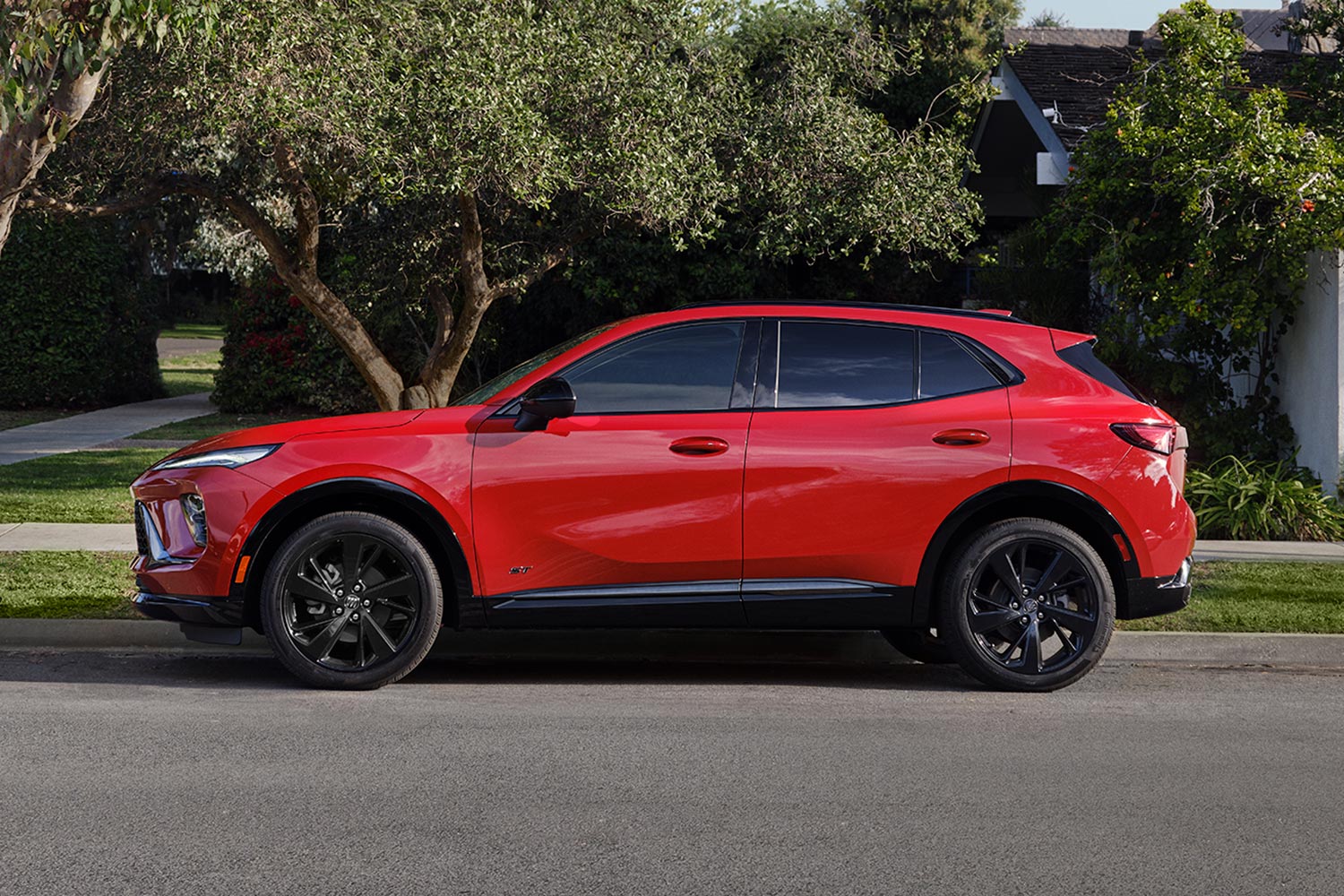 A Red Buick SUV with Black Wheels Parked on a Suburban Street with Trees