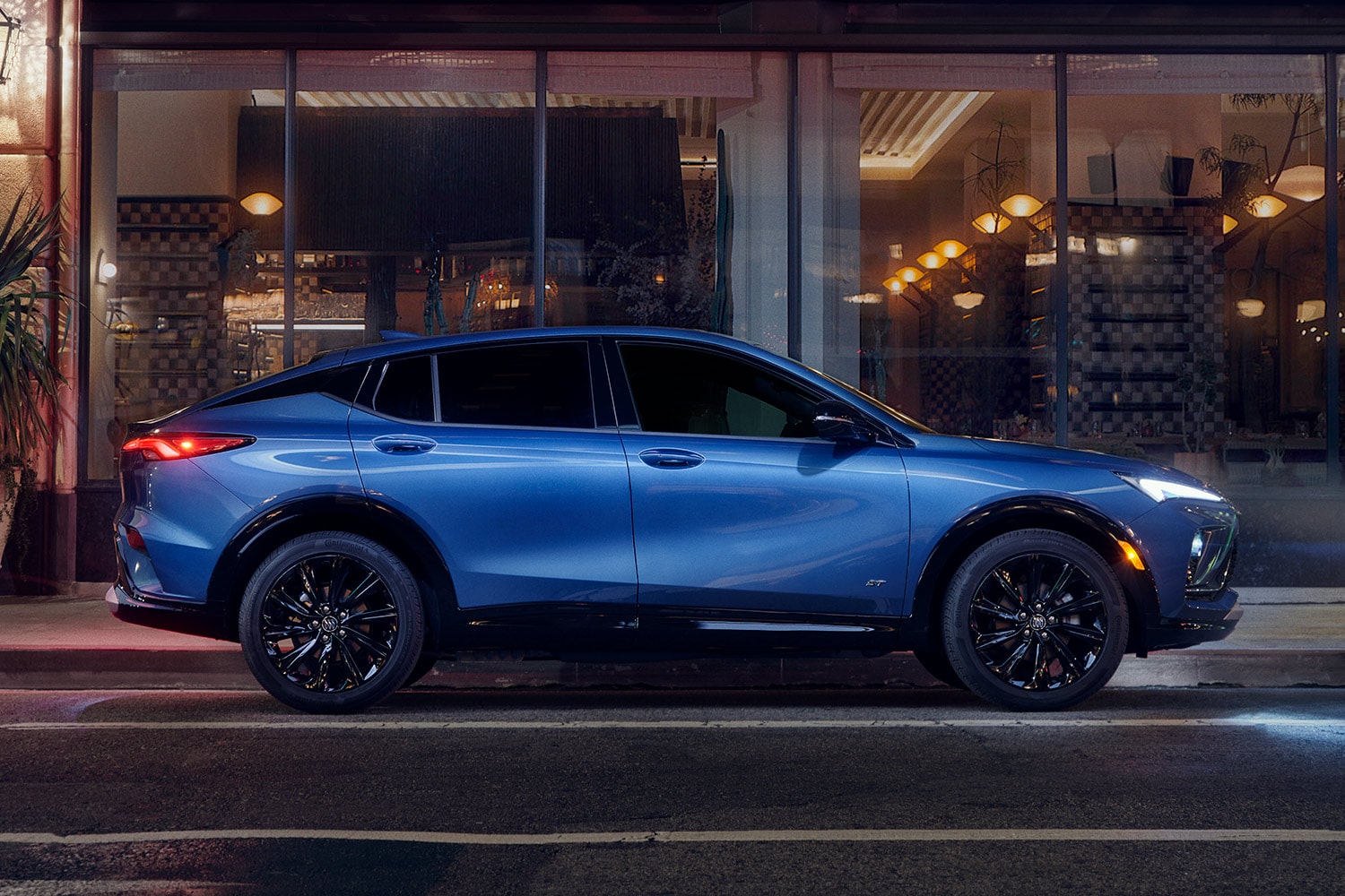 A Blue Buick Crossover with Black Wheels Parked on a City Street at Night