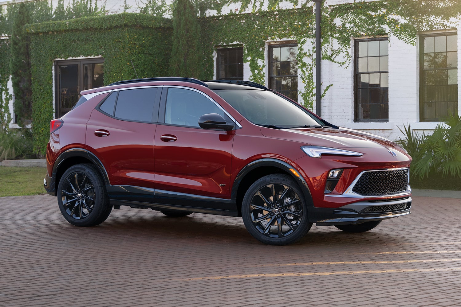 A Red Buick SUV Parked on a Driveway in Front of a House Covered in Green Ivy