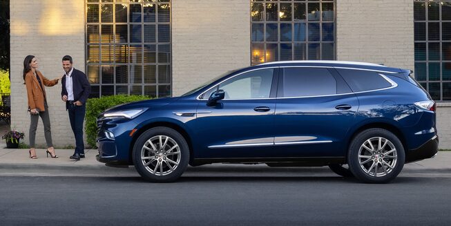 The Blue Buick Enclave Parked Next to Two People On-Road