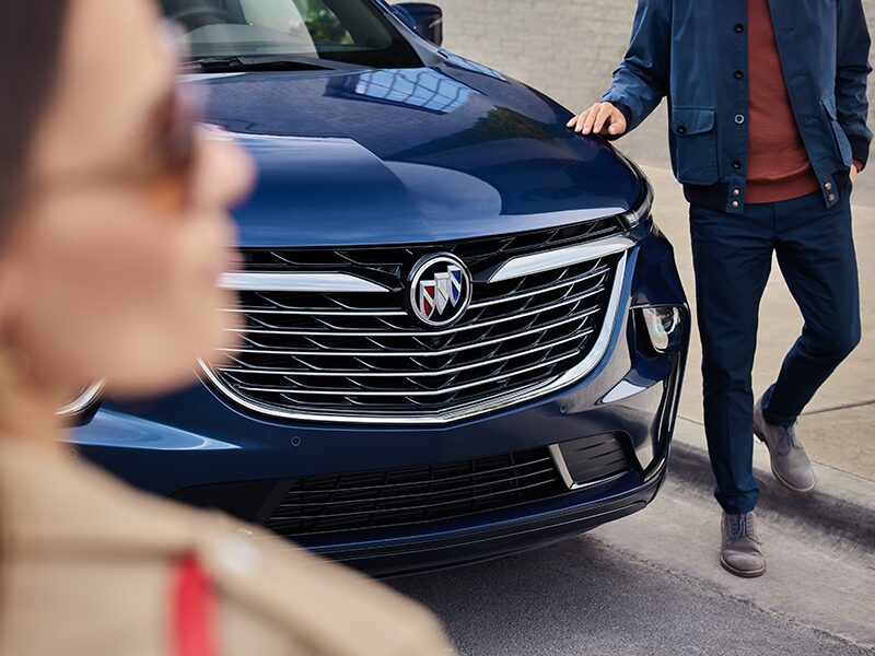 A Man Touches the Hood of the Buick Enclave As He Walks Around the Car to Meet His Wife