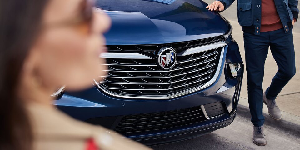 A Man Touches the Hood of the Buick Enclave As He Walks Around the Car to Meet His Wife