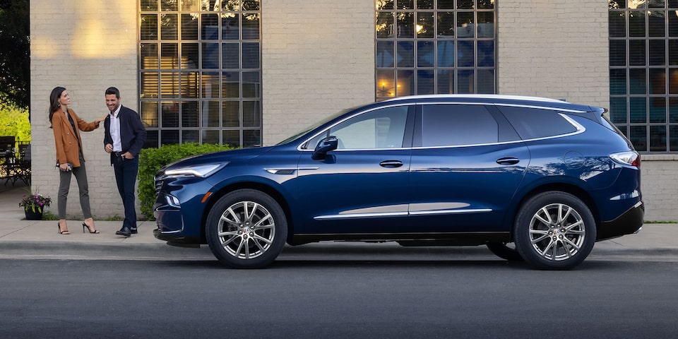 The Blue Buick Enclave Parked On-Road next to two people