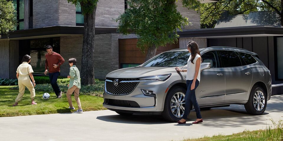 A Family playing Soccer in their Front Lawn next to their Buick Enclave