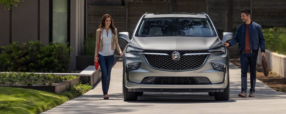 A Couple reaches for the Doors of Their 2024 Buick Enclave Parked in The Driveway of Their Home