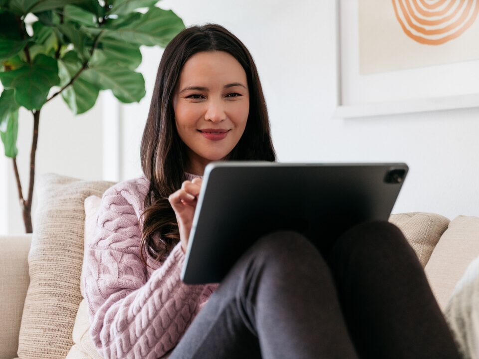 A women using a Tablet while sitting on a coach in a Living Room