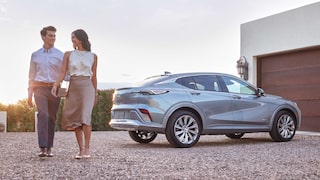 A Couple Walking Away from a Parked Silver Buick Envista Avenir