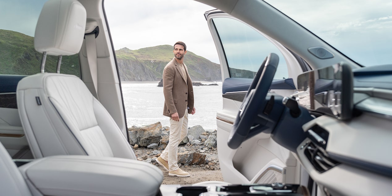 Side View of a 2025 Buick Enclave Front Interior with the Door Open and a Man Standing Outside