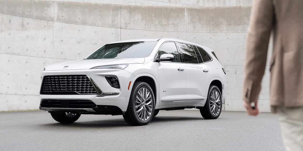A Person Approaching a White 2025 Buick Enclave Surrounded by Walls