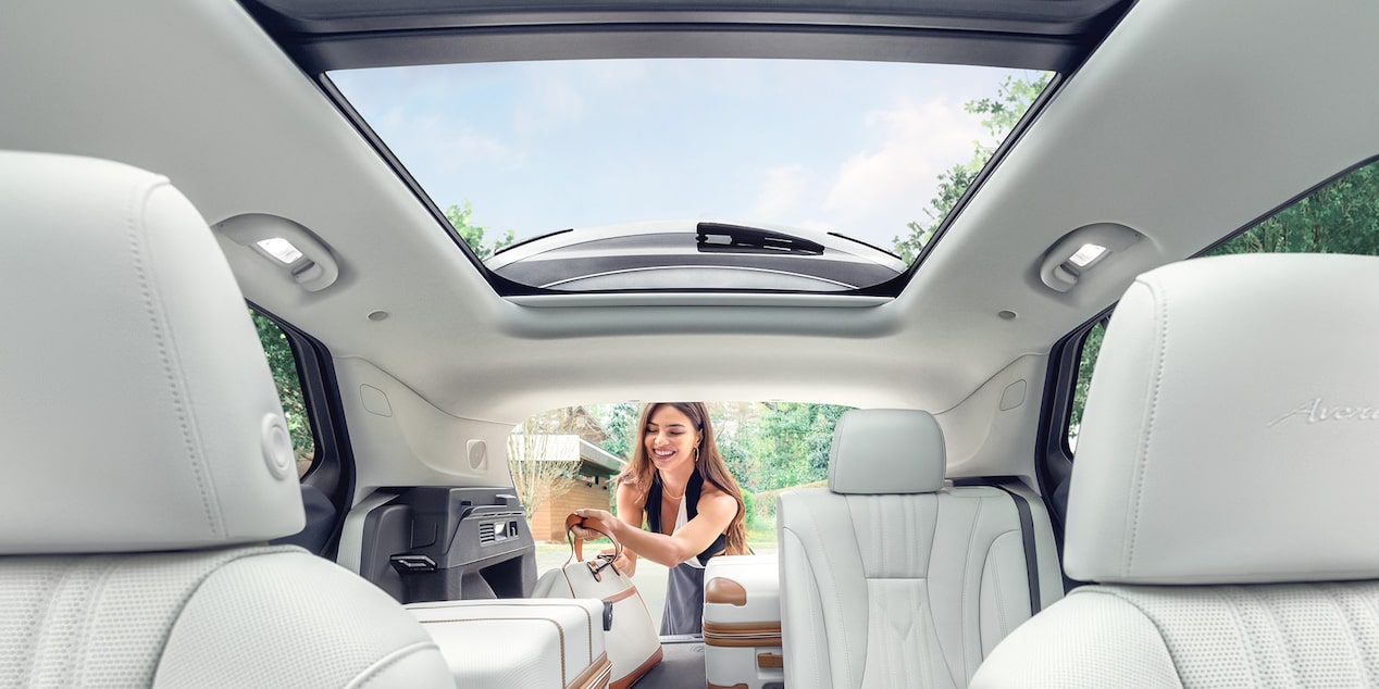 Interior View of a 2025 Buick Envision 5 Passenger SUV with a Person Loading Luggage Into the Trunk