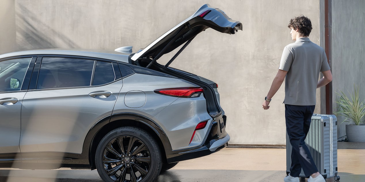 A Man with Luggage Walking to the 2025 Buick Envista and Utilizing the Power Liftgate Feature
