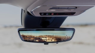 Close-up of the Rear View Mirror Showing a Desert with Fences